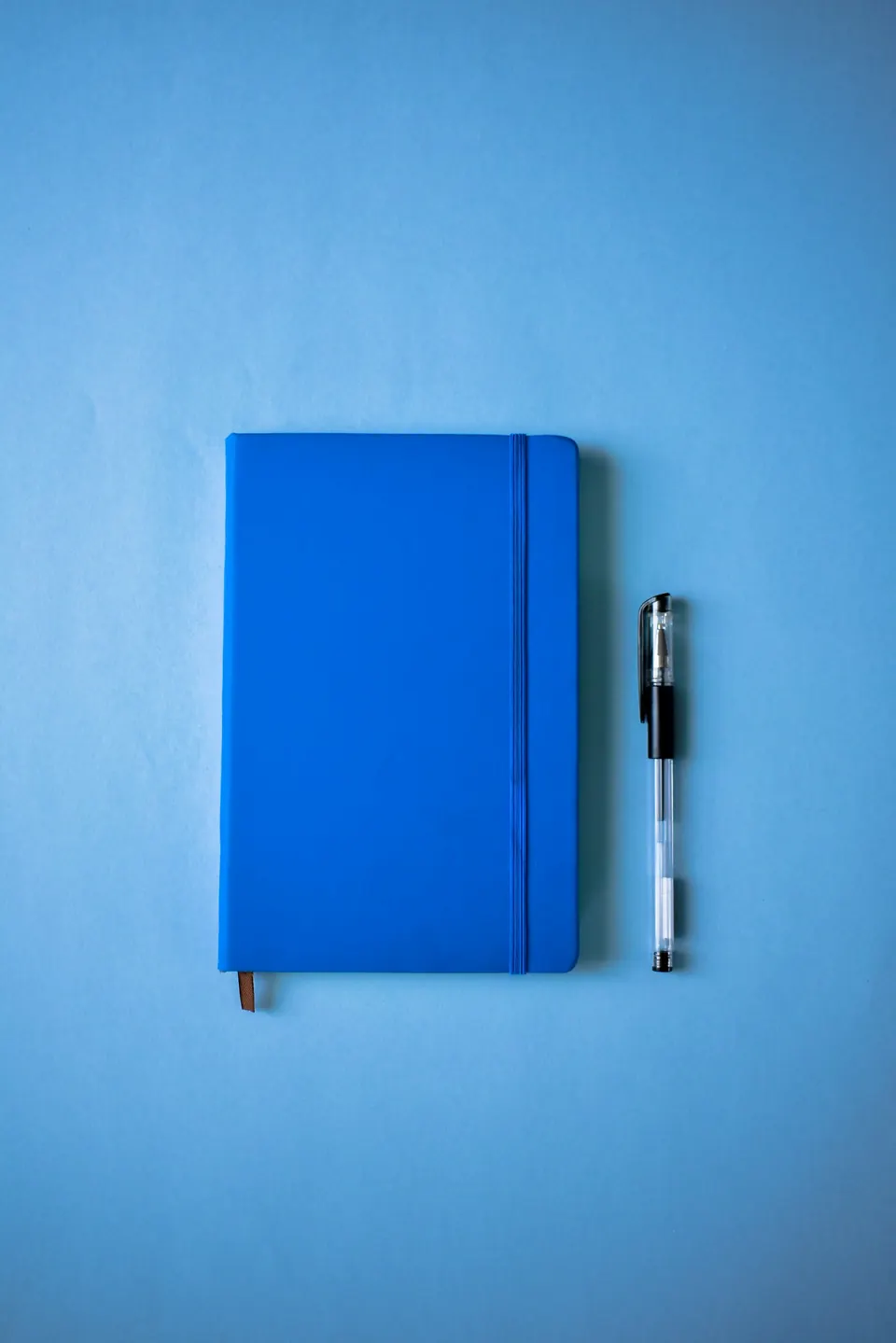 A blue hard-bound journal and a pen on a blue desk
