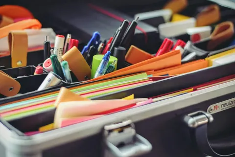 An organiser case full of pens, sticky notes and coloured paper