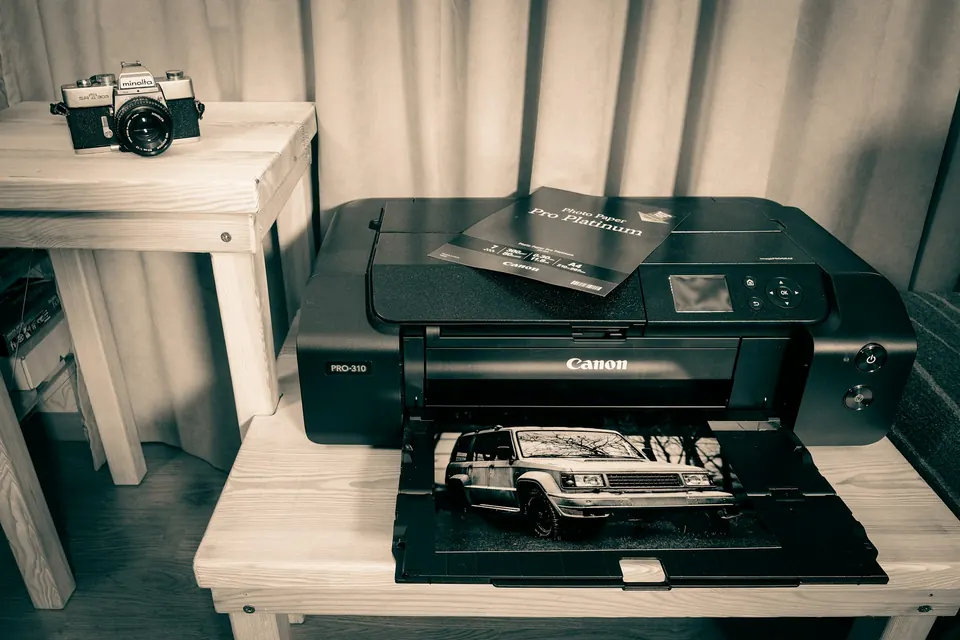 A printer feeding out a photograph beside a vintage film camera