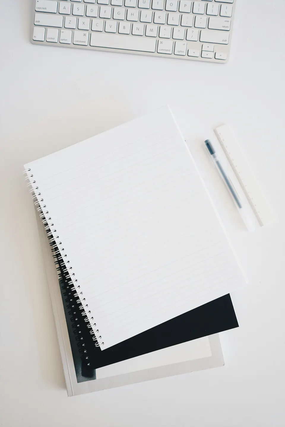 A blank spiral-bound notebook lying next to a keyboard